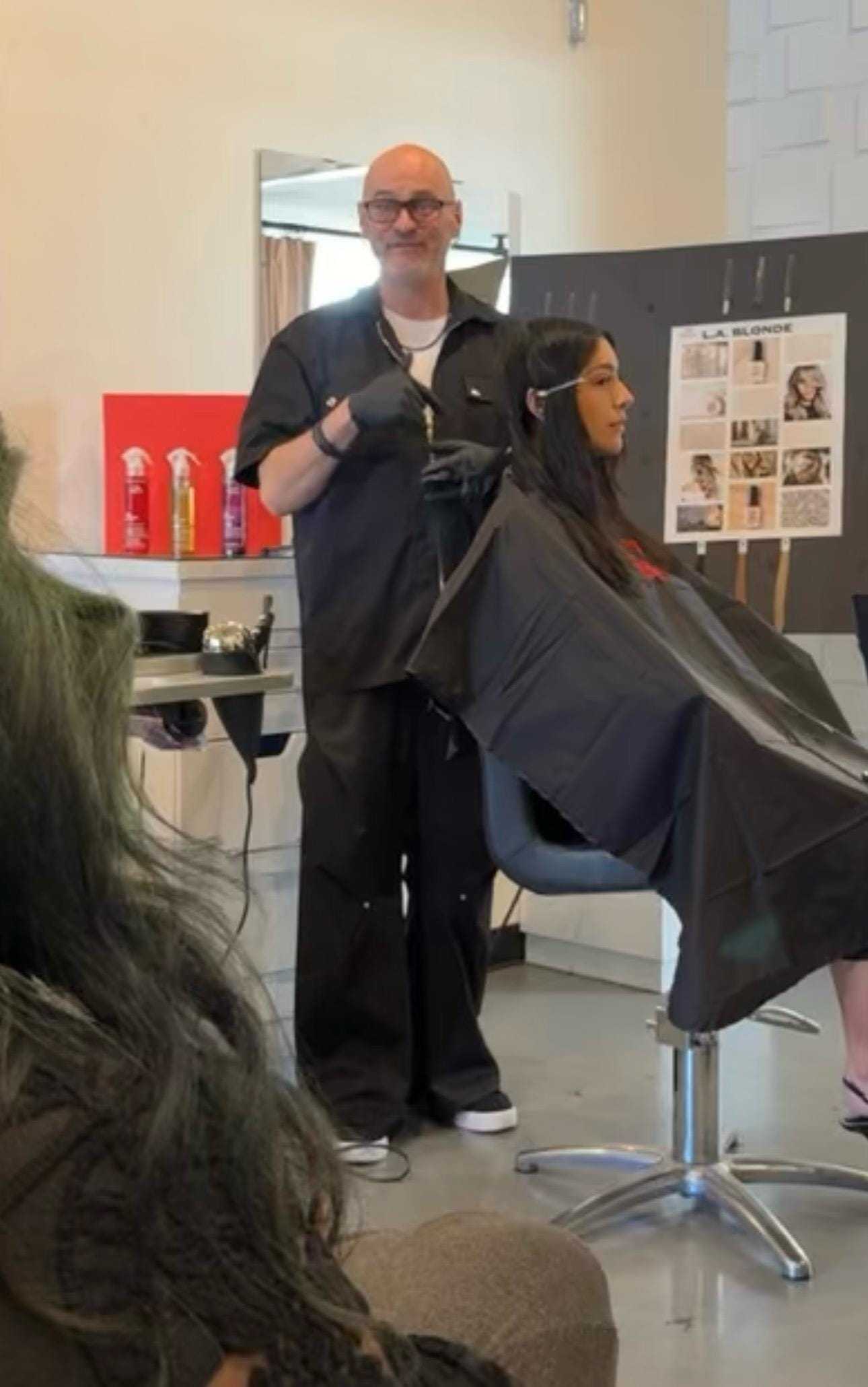 Hair stylist working on client's hair in a salon setting, with products displayed nearby.