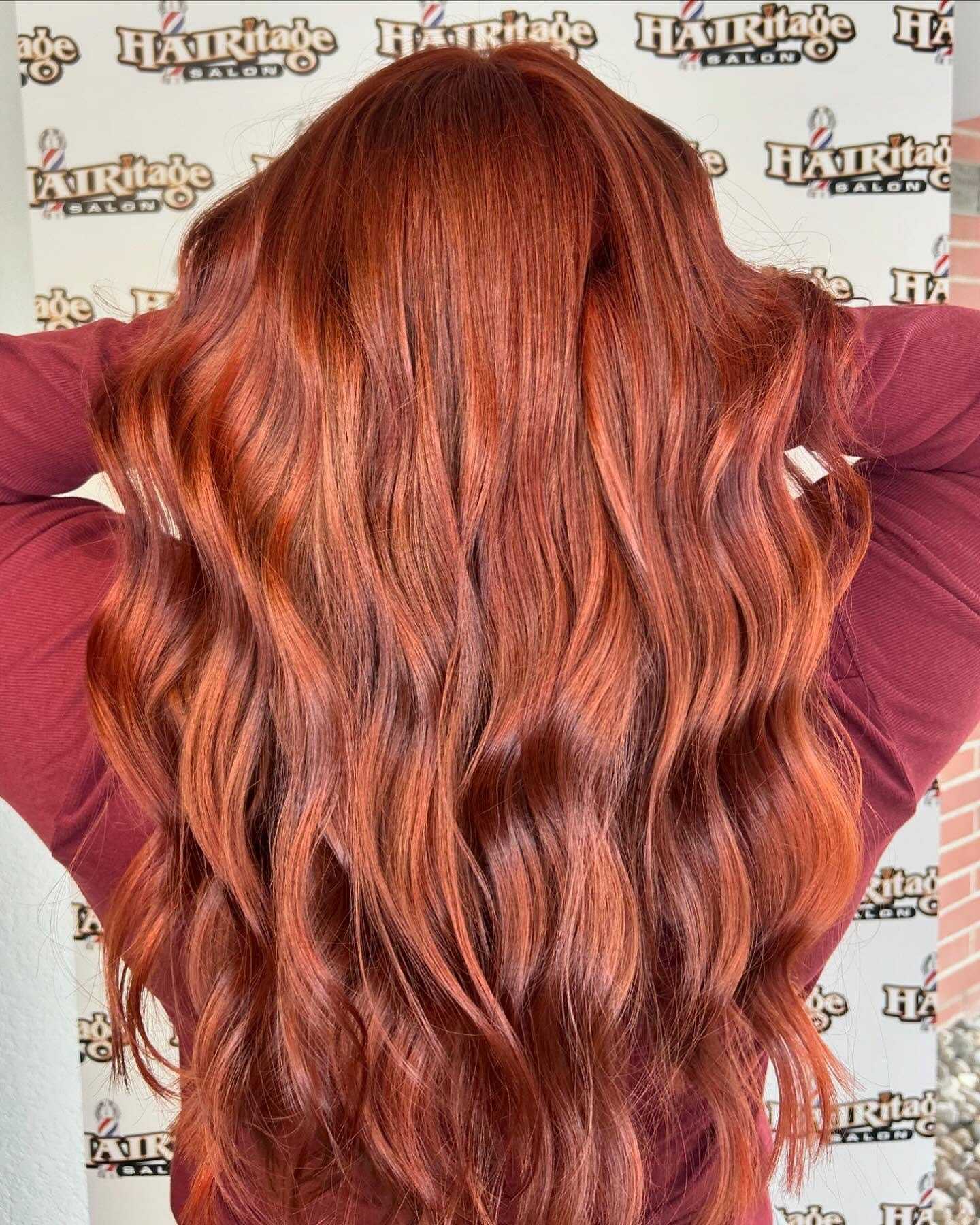 Long wavy red hair with vibrant color, styled in loose waves.