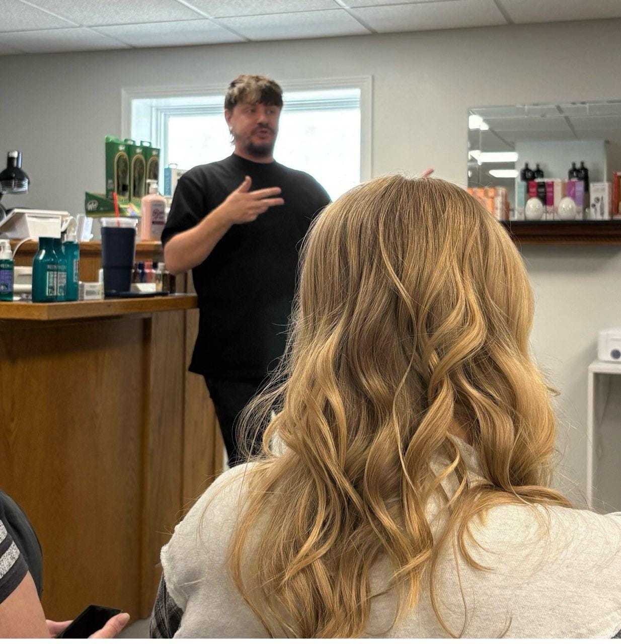 Person giving a presentation about hair care products in a salon setting.